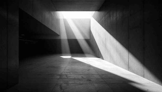 A dark, dramatic concrete corridor illuminated only by a single sliver of sunlight