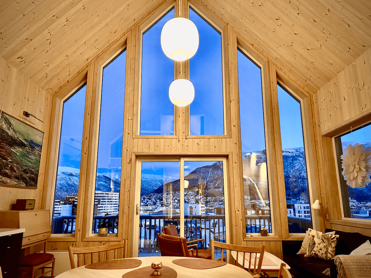 Interior of a cabin with a large picture window framing a snowy forest